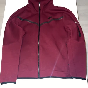 Vinröd nike tech fleece - Hej säljer en nästan helt ny vinröd nike tech fleece, väldigt fint skick denna färg finns inte heller i butiker  längre vilket gör den mer eftertraktad. Köptes för cirka 2,300kr (denna tracksuit finns även i storlek S)