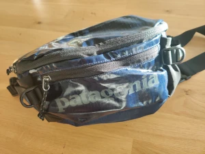 NY Patagonia midjeväska / sling bag - Helt NY och oanvänd väska, mörkblå och svart. Fick denna i present men är lite för stor för mig.  Hämtas i Malmö-området eller skickas. Priset är fast, använd EJ "Köp Nu"-funktionen. Skriv istället vid frågor eller intresse. Köpare betalar ev. frakt.