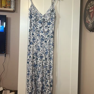 Sommar Onepice  - Sommar onepiece i bomull. Vit med blått mönster. Volang i krage. Dragkedja i rygg. Använd ett fåtal gånger.  Strl. 38