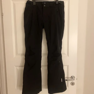 Svarta skidbyxor - Svarta skidbyxor i fint skick, de har använts endast en säsong. I storlek 36. De är vadderade med vattentätt yttertyg och har RECCO-system i sig. 