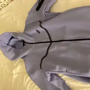 En lila Nike tech fleece som inte använts så mycket. Den är nästan helt ny och där är inga hål, fläckar eller andra defekter.