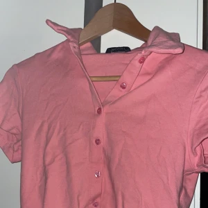 Rosa polotröja  - Säljer denna croppade, rosa polotröja från Monki eftersom den inte kommer till användning längre. Vill mest bli av med den så säljer billigt :) säljer 3 för 2, annars utsatt pris :)