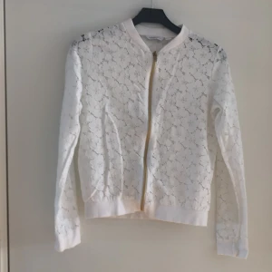 Vit kort jacka i spets från KappAhl - Snygg jacka i vit spets från KappAhl. Använd endast ett få tal gånger. Väldigt fräsch! Storlek 158/164 