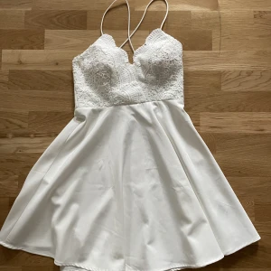 Vit klänning - En superfin klänning som endast är använd under konfirmation för några år sedan. Har en dragkedja i sidan. Tjockare tyg och korsade smala axelband. Mått från axel och ned: ca 87cm. Hade tyvärr inte jättebra bild i klänningen.