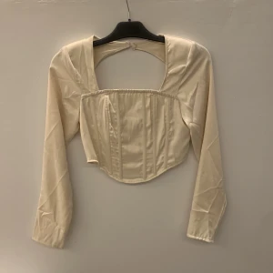 Satintopp med öppenrygg - Långärmad korsett topp i satin med öppen rygg från missguided. Endast använd 1 gång,  jättefin på. 