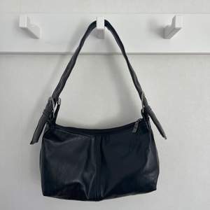 En svart väska i skinn som är vintage och justerbar i banden. Hör av dig vid frågor 😗