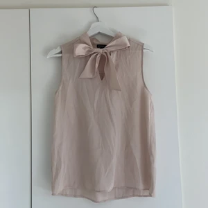 Söt blus i bra skick - Champangefärgad blus från MQ med rosett. Fint skick, endast använd fåtal gånger. Köparen står för frakten.