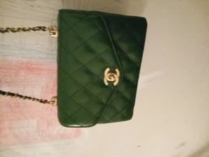 Äkta Chanel mörkgrön handväska nyskick  - En söt grön äkta Chanel söt 45cm lägnd från höger till vänster från botten till locktopp 30 cm hårt slitstarkt. Äkta läder 10cm bred om den är fullpackad . Långt axelräm flätad i gröntläder och guld rött tyg inuti fick den av min xman vid bröllop  