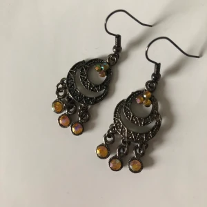 Iridescent gula örhängen  - Örhängen med gula strassar i mörk metall, i gott skick! Men dm:a mig gärna vid frågor. Köparen står för frakt (15kr).