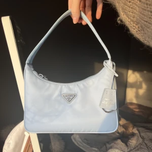 Prada väska  - Tänkte kolla ifall det är någon som har en äkta Prada re-edition 2000 i svart eller brun i bra skick som skulle kunna tänka dig byta mot min i en såå fin blå färg. Den är köpt i Prada butiken i Stockholm —> äkthetsbevis finns (Säljer alltså inte väskan)