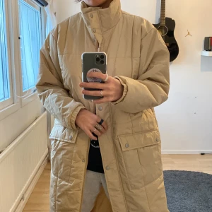 Lång jacka från NA-KD! - Beige lång jacka från NA-KD i storlek 38. Nytt skick endast testad samt dragit bort prislapp. Ordinariepris: 599:- men säljer den för 180kr!