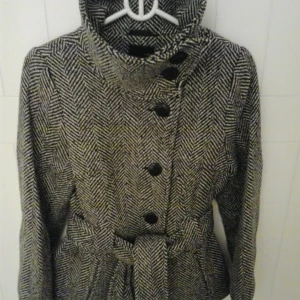 NY & HELT OANVÄND Svart/vit snygg damjacka / höstjacka. Strlk: 34 / XS-SMALL. - HELT NY och OANVÄND felfri snygg svart / vit mönstrad höst/vinter/vårjacka med sk "fiskbensmönster". Storlek: 34/XS-SMALL. Material: Värmande Ull mfl blandade material. Fodrad med satinfoder. Snygga ärmar. Har knytskärp i midjan, 2 fickor fram, knappar.