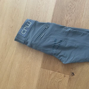 Ridbyxor CRW - Säljer dessa sjukt bekväma ridbyxor i en snygg grå färg med fäste rumpan och längst benen. Jag är i vanliga fall en 36/38 men dessa i 34 får jag på mig i och med att det är sjukt strechiga. Jätte bekväma att rida i och fickor som rymmer en del. Aldrig fått så bra fäste på sadeln och barbacka som i dessa brallor. Köpta för 899 eller 999kr och säljer för 399. Inga skavanker ser precis ut som nya. Har ridit sommartid och vintertid, passar alla årstider. har ett vattenavvisande material