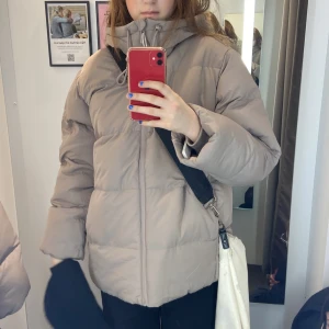 Jacka beige - Beige vinterjacka köpt på Stadium denna vinter. Endast använd några få  gånger utan tecken på användning. Strl. 36, men funkar som S/M. Justerbar luva och mjukt värmande material i fickorna och innefoder. ☺️ Pris kan diskuteras vid snabb affär!