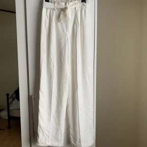 Vita byxor från BikBok - Vita kostymbyxor från BikBok. Dubbelt tyg och är därför inte genomskinlig som andra vita byxor 😍går att knyta runt midjan för att framhäva midjan ytterligare!