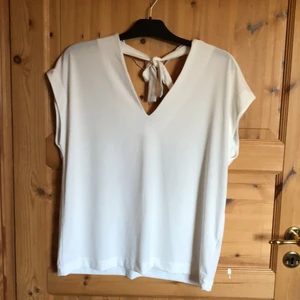 Vit top med knyt i nacken - Nyskick. V-ringad fram och bak. Knyts i nacken.   Frakt ingår