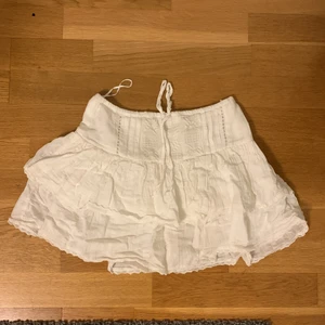 Volangkjol med broderade detaljer  - Söt kjol med volanger och med shorts under! Fina broderade detaljer. Knappt använd, nästan ny! 