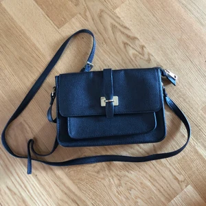 Svart väska - Svart klassisk väska i läderimitation. Tre yttrefack och ett fack med dragkedja på insidan. (Fraktpris gäller för köp via Plick)