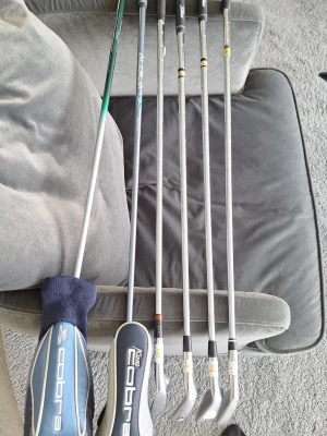 Golfklubbor Cobra och andra märken - Säljer ett set med fem golfklubbor, blandat mellan järnklubbor och drivers. Två av klubborna har blåsvarta Cobra-headcovers. Skaften är i metall och greppen är svarta. Perfekt för dig som vill börja spela golf eller komplettera din samling.. driver. 3 Woods. 5 iron 7iron pitch 8 iron. 120kr per klubba kan gå ner vid snabb affär 