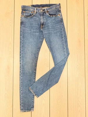 Blå Levi's skinny jeans - Snygga blå skinny jeans från Levi's med klassisk femficksmodell och normalhög midja. Jeansen har en ljus tvätt och raka ben. Tillverkade i slitstark denim med Levi's ikoniska läderpatch bak i midjan.