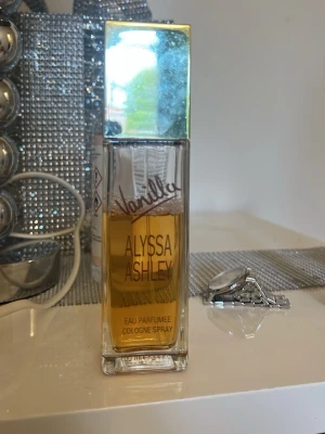 Alyssa Ashley Vanilla parfym - Alyssa Ashley Vanilla Eau Parfumée Cologne Spray i en rektangulär glasflaska med spegelblankt silverlock. Doften har en varm vaniljkaraktär och flaskan har tydlig text i guld och brunt. Perfekt för dig som älskar söta och mjuka dofter. 100ml ca 70 kvar