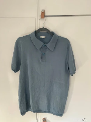 Polo från Sandro - Snygg ljusblå polo från Sandro. Liten defekt (fråga om bild om du vill se närmare). Storlek S