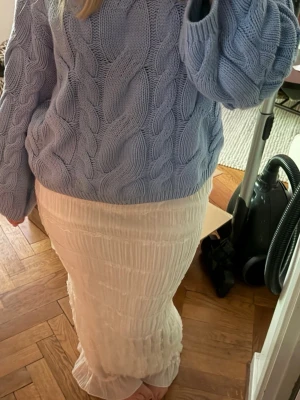 Vit långkjol med volangdetaljer - Säljer en vit långkjol med fina volangdetaljer. Kjolen har en smal passform och är tillverkad i ett lätt, mjukt material som ger ett flowy intryck. Perfekt för dig som gillar en stilren och feminin look.