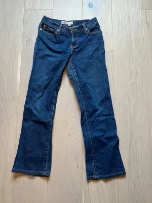 Y2k jeans med coola fickor - Snygga mörkblåa raka jeans med dekorativa bakfickor. Från märket Born In California. Storleken på lappen stämmer inte, utan de är omsydda för att passa barnstorleken 152/158 cm. Lite slitet längst ner och vissa av paljetterna har fallit av, men det är inget som jag tycker att man tänker på