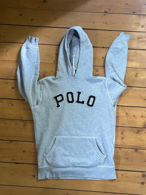 Polo Ralph lauren hoodie. - Snygg grå hoodie med stor huva och POLO-tryck i svart och vitt på bröstet. Klassisk känguruficka framtill och ribbade muddar vid ärmar och nederkant. Perfekt för en avslappnad stil. Hör av er vid frågor. 