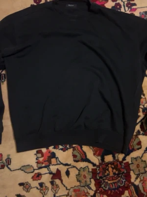 sweatshirt Hugo Boss - Klassisk svart sweatshirt från Hugo Boss med diskret broderad logga på bröstet. Tröjan har rund halsringning, långa ärmar och ribbade muddar vid ärmslut och nederkant. Perfekt för en clean och stilren look. Obs!! Är osäker på storlek eftersom det står inte på tröjan men jag gissar på S/M eftersom det är den storleken jag har på mina andra kläder och den passar mig! Tröjan sitter lite baggy. 