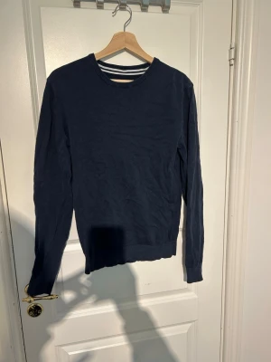 Mörkblå tröja från Pier One - En stilren mörkblå tröja från Pier One med rund halsringning och ribbade muddar vid ärmslut och nederkant. Perfekt basplagg som funkar till det mesta. Tillverkad i mjukt material för en bekväm känsla.
