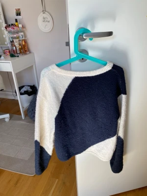 Blåvit stickad tröja från Gina Tricot - Säljer en snygg stickad tröja från Gina Tricot i storlek 134/140. Tröjan har ett coolt blockmönster i mörkblått och vitt, rund halsringning och långa ärmar. Perfekt för dig som gillar en avslappnad och trendig stil.