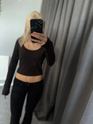 Svart croppad långärmad topp SHEIN - Säljer en svart croppad långärmad topp från SHEIN i ribbad polyester. Toppen har en rund halsringning och sitter tight mot kroppen, perfekt för en trendig och enkel look.