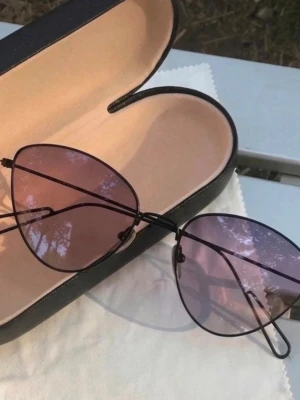 Lila hjärtformade solglasögon - Unika solglasögon med hjärtformade linser i en snygg lila ton. Tunn svart metallbåge och näskuddar för extra komfort. Perfekt accessoar för dig som vill sticka ut och addera en lekfull touch till din stil.