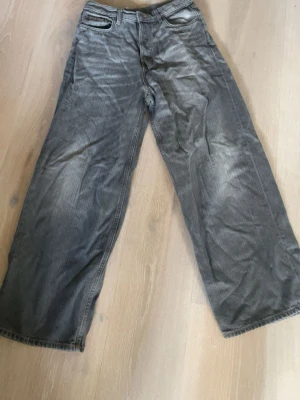 Gråa wide leg jeans - Säljer ett par gråa jeans med breda ben och hög midja. Jeansen har klassisk femficksdesign och raka sömmar. Materialet är denim i bomull och färgen har en tvättad look som ger en avslappnad vibe.