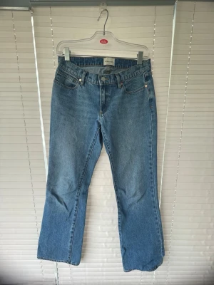 Blå bootcut jeans i klassisk modell - Säljer ett par blå bootcut jeans med fem fickor och normalhög midja. Jeansen har en klassisk denimlook med raka ben och är tillverkade i bomull. Perfekta för dig som gillar en tidlös och avslappnad stil.