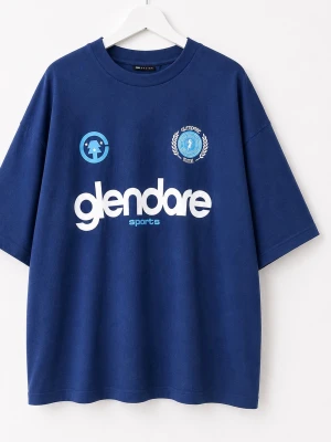 Blå oversized t-shirt med tryck - Säljer en mörkblå oversized t-shirt med vit och ljusblå text och logga framtill. T-shirten har rund hals och korta ärmar. Perfekt för en avslappnad och sportig stil.