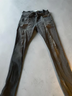 Gråa Zara jeans i denim - Säljer ett par gråa jeans från Zara i denim med klassisk femficksmodell och dragkedja. Jeansen har en smal passform och är tillverkade i ett mjukt material som sitter snyggt. Perfekta för dig som gillar en stilren och enkel look.