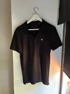 Lyle & scott Piké - Svart Piké från Lyle&scott med krage och emblem på bröstet, perfekt till skolstarten