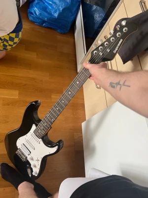 Supreme elgitarr och förstärkare - Säljer ett paket med svart Supreme elgitarr i klassisk Stratocaster-stil och en Supreme GA-10 förstärkare. Gitarren har vit plektrumskydd och flera reglage. Förstärkaren har kontroller för gain, volym, bas och diskant samt hörlursuttag. Perfekt för dig som vill börja spela elgitarr.
