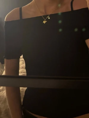 Svart offshoulder topp - Säljer en svart offshoulder topp med smala axelband och korta ärmar. Toppen har en åtsittande passform och är gjord i ett stretchigt material som ger en snygg siluett. Perfekt att styla med jeans eller kjol för en trendig look.