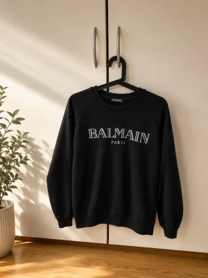 Svart sweatshirt från Balmain - Stilren svart sweatshirt från Balmain med vit logotyptext på bröstet. Tröjan har rund halsringning och långa ärmar. Tillverkad i mjukt material som ger en avslappnad och trendig look.