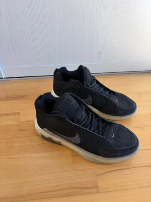 Svarta Nike basketskor med vit sula - Snygga svarta basketskor från Nike med en chunky vit sula och diskret swoosh på sidan. Ovandelen är i mesh och syntetmaterial för bra andningsförmåga och komfort. Klassisk snörning och vadderad häl för extra support.