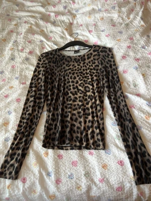 Leopardmönstrad mesh topp - Snygg långärmad topp i mesh med leopardmönster. Toppen har en tight passform och rund halsringning. Perfekt för dig som vill sticka ut lite extra med ett djurmönster.