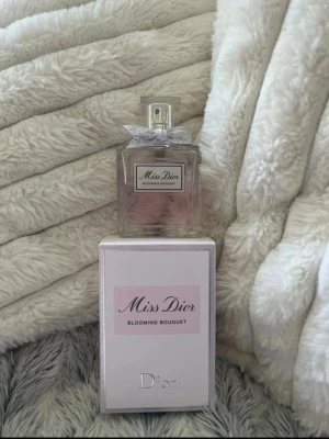 Miss Dior Blooming Bouquet parfym  - Miss Dior Blooming Bouquet är en elegant parfym i en genomskinlig glasflaska med en söt liten rosett vid halsen. Doften är blommig och fräsch, och flaskan har en stilren, lyxig design. 50 ml