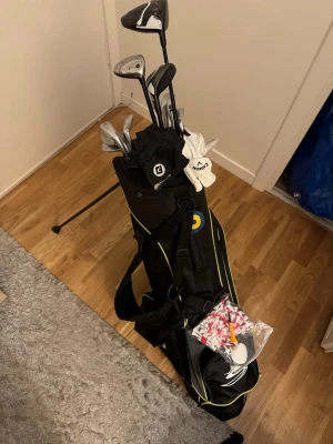 Golfset med bag och klubbor - Buda på är öppen för bud! Kommer behövas hämtas/skickas på annat sätt.  flera golfklubbor i olika modeller samt tillbehör som peggar och bollar. Bagen har axelrem och flera fack, perfekt för att ta med på rangen, vissa med headcovers. Drivern och big bertha eller puttern är dyrast då den är gjord med carbon fiber osv.  Utöver klubborna( pitching wedge, järn från cobra 9,8,7,6,5, 56 graders, big bertha 7, spalding sx putter.2 handskar, många peggar, några golfbollar, en cobrabag osv. Fråga på!