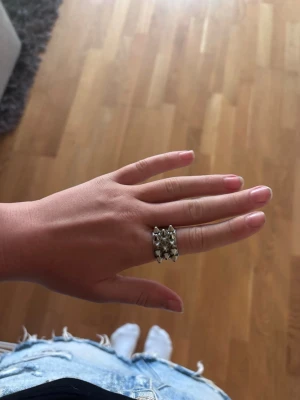 Silvrig ring från Edblad  - Cool ring i silverfärgad metall med flera små konformade nitar runt hela ringen. Ringen har en bred design och ger ett edgy intryck, perfekt för dig som gillar att sticka ut med dina accessoarer.