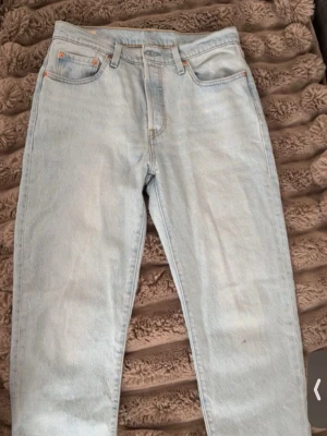 Ljusblå raka Levi's jeans - Säljer ett par klassiska ljusblå Levi's jeans med rak passform och hög midja. Jeansen har fem fickor, gylf med knappstängning och den ikoniska röda Levi's-lappen på bakfickan. Avklippta nedtill, dem hamnar vid mina anklar och jag är 163, därav de billiga priset trots att dem knappt är använda 