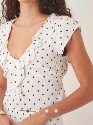 Vit prickig croppad blus med volang - Söt vit croppad blus med svarta prickar, djup v-ringning och volangkant längs urringningen. Köpt på mango storlek xs. 💕