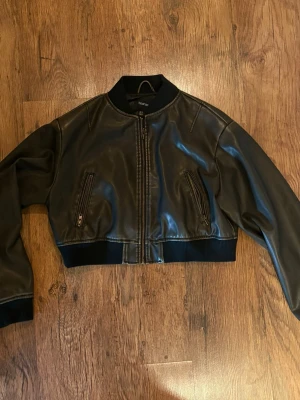 Svart cropped skinnjacka - Snygg svart cropped skinnjacka med dragkedja framtill och två fickor med dragkedja. Jackan är endast använd fåtal gånger.